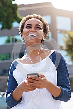 Beautiful young black woman laughing with earphones and cellphone