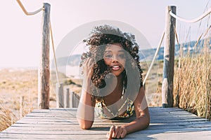 Beautiful young black woman lying down in a wooden foot bridge