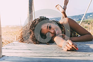 Beautiful young black woman lying down in a wooden foot bridge