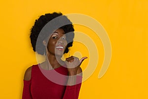 Beautiful Young Black Woman Is Pointing At Yellow Wall With Thumb