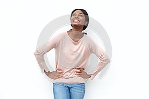 Beautiful young black woman smiling with hands on hips and looking up