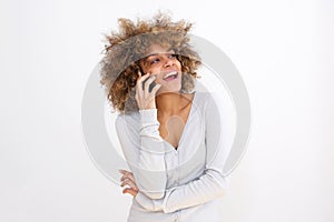 Beautiful young black woman talking on cellphone against whit background