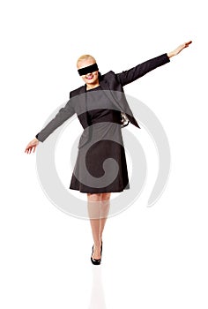 Beautiful young blindfolded businesswoman trying walk