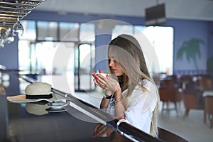 Beautiful young blond drinking coffee. attractive girl sitting in cafe. Relaxing. Summer vacation. Summertime