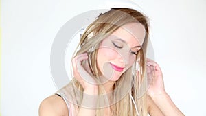 Beautiful young blond woman dancing with white headphones