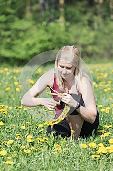 Beautiful young blond woman is making a wreath of dandelion blossoms