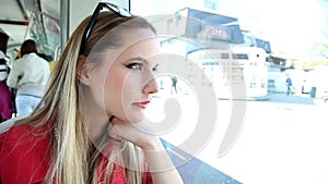 Beautiful young blond woman riding tram, looks abstracted