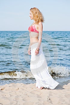 Beautiful young blond woman walking on a beach