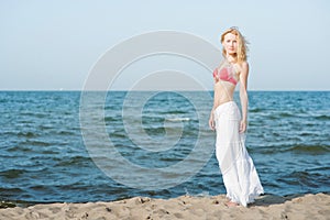 Beautiful young blond woman walking on a beach