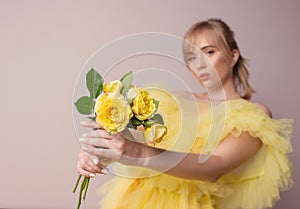 Beautiful young blonde caucasian woman in yellow dress with yellow roses. t