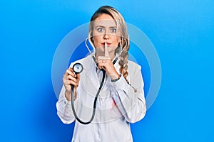 Beautiful young blonde doctor woman holding stethoscope asking to be quiet with finger on lips