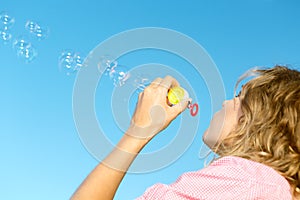 Beautiful young blonde girl blowing soap bubbles