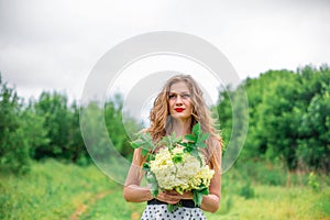 A beautiful young blonde girl collected a bouquet of wildflowers. Enjoy a walk on a warm summer day