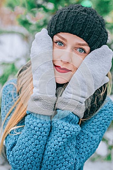 Beautiful young blonde girl in hat and mittens covers his face outside in the cold, Effect retro photo, grain