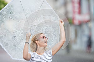 Beautiful young blonde girl holding umbrella in summer rain