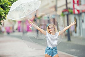 Beautiful young blonde girl holding umbrella in summer rain