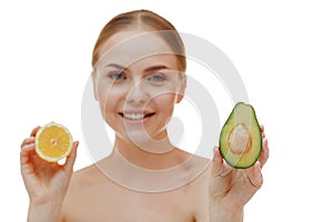 A beautiful young blonde girl holds half an avocado and half a lemon in her hands. Isolated on white background. The concept of