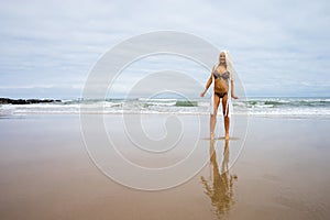 Beautiful young blonde haired woman on the beach in bikini smiling