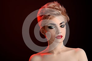 Beautiful young blonde red lipped woman posing in artistic red lighting