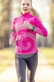 A beautiful young blonde in sportswear is training for running in the park