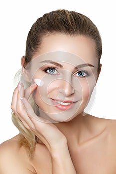 Beautiful young blonde woman applying moisturizing face cream