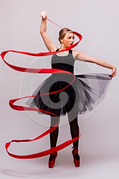 Beautiful young blonde woman ballet gymnast training calilisthenics exercise with red ribbon with red shoes