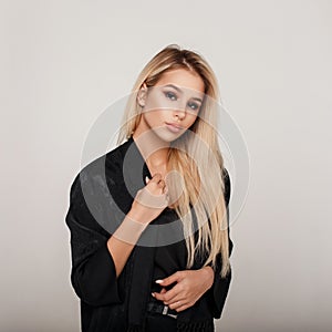 Beautiful young blonde woman in a black fashion dress in studio
