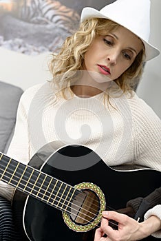 beautiful young blonde woman with hat playing the acoustic guitar