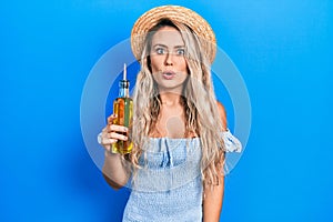 Beautiful young blonde woman holding olive oil scared and amazed with open mouth for surprise, disbelief face