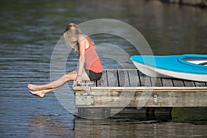 Beautiful young blonde woman kayaking on lake