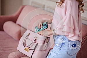 Beautiful young blonde woman with light pink handbag and mobile phone