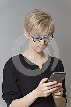 Beautiful young blonde woman looks emotionally at the smartphone