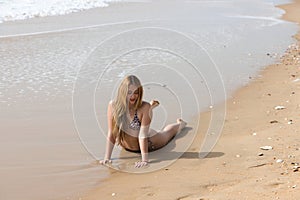 Beautiful young blonde woman lying on the shore of the beach. The woman is sunbathing and enjoying the holiday and the sea. Travel