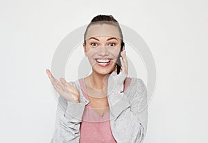 A beautiful young blonde woman picks up the news on the phone and is surprised. Great news! Over white background.