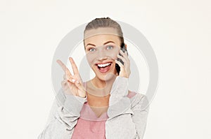 A beautiful young blonde woman picks up the news on the phone and is surprised. Great news! Over white background.