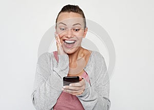 A beautiful young blonde woman picks up the news on the phone and is surprised. Great news! Over white background.