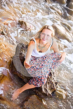 Beautiful young blonde woman posing outdoor at the rocky sea shore