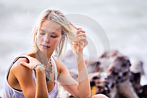 Beautiful young blonde woman posing outdoor at the rocky sea shore