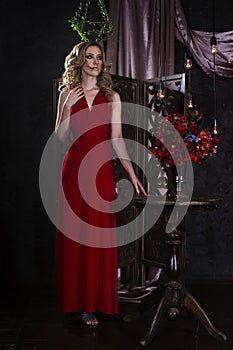 Beautiful young blonde woman in red dress with halloween make up and bloody face art