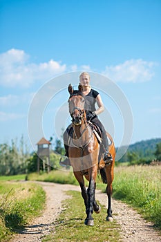 Beautiful young blonde woman riding a horse