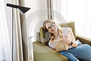 Beautiful young blonde woman sitting in armchair