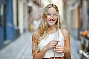 Beautiful young blonde woman smiling in urban background.