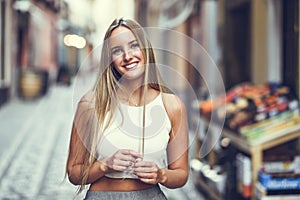 Beautiful young blonde woman smiling in urban background.