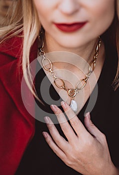 Beautiful young blonde woman in a trendy autumn dress in burgundy Marsala color with a necklace on her neck. Soft selective focus