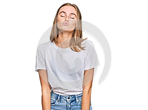 Beautiful young blonde woman wearing casual white t shirt looking at the camera blowing a kiss on air being lovely and sexy
