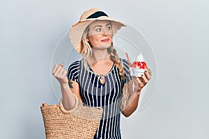 Beautiful young blonde woman wearing summer style eating ice cream smiling looking to the side and staring away thinking