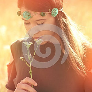 Beautiful young boho woman in summer meadow hold flower sunlight