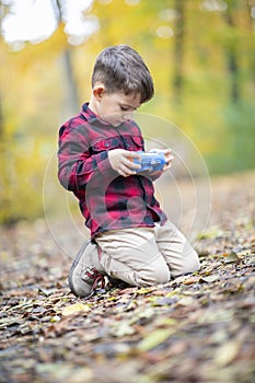 Beautiful young boy playing with a kid camera outside