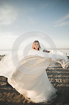 Beautiful young bride with bridal bouquet posing on the background sea