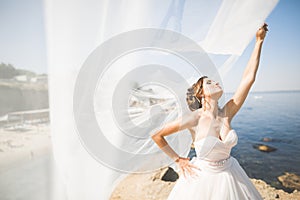 Beautiful young bride with bridal bouquet posing on the background sea